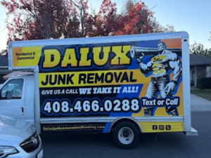 Dalux Junk Removal box truck with company logo and phone number parked on a residential street.