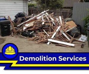 Residential demolition services banner showing a large pile of construction debris and wood scrap on a driveway.